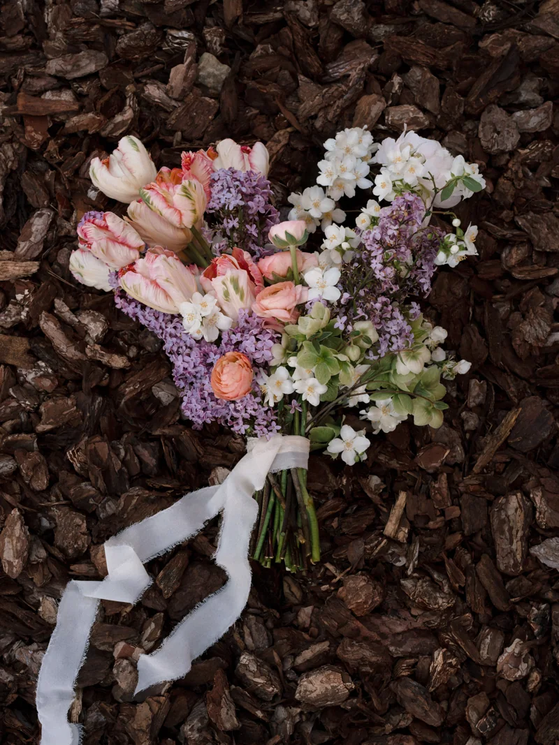 Bouquet di fiori bianchi, rosa e lilla appoggiato sulla corteccia
